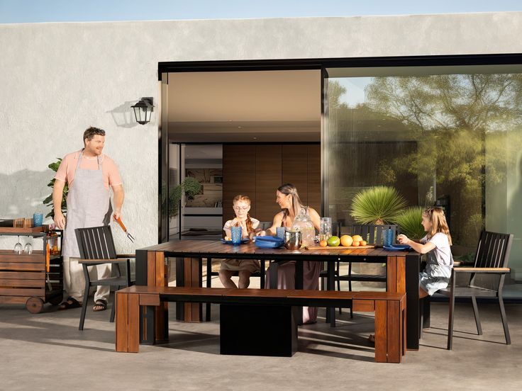 a family sitting around a table outside on the patio with their child's food