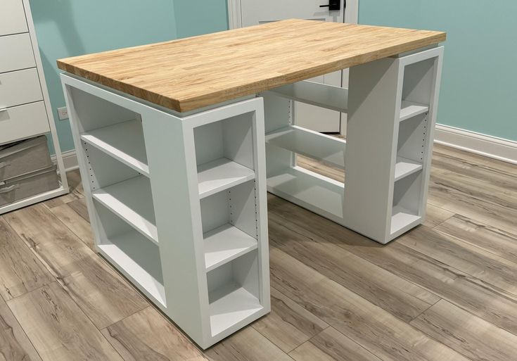 an office desk with shelving units in the corner and drawers at the end, on a hard wood floor