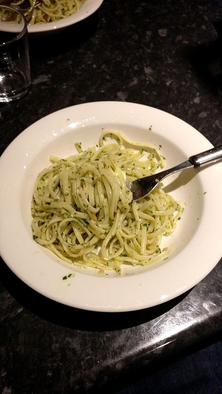 a white plate topped with pasta on top of a table