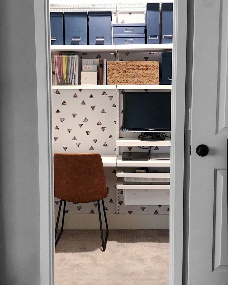 a chair sitting in front of a computer monitor on top of a wooden desk next to a bookshelf