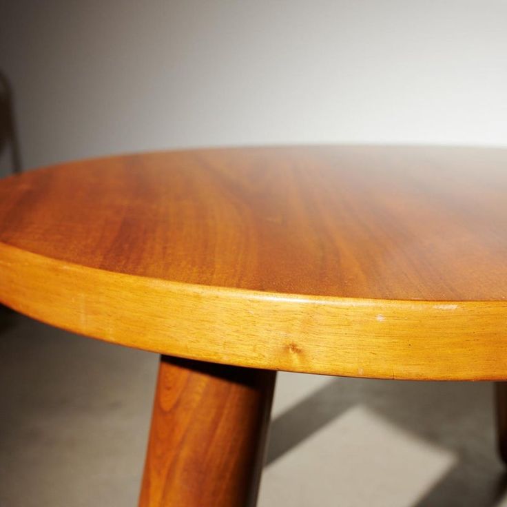 a close up of a wooden table with chairs in the backgroung behind it