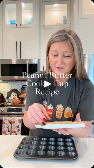 a woman is holding up some cupcakes in front of an oven with the words peanut butter cookie cup recipe on it