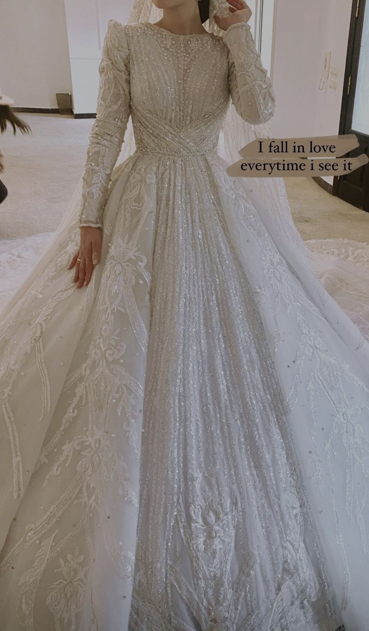 a woman in a white wedding dress with long sleeves