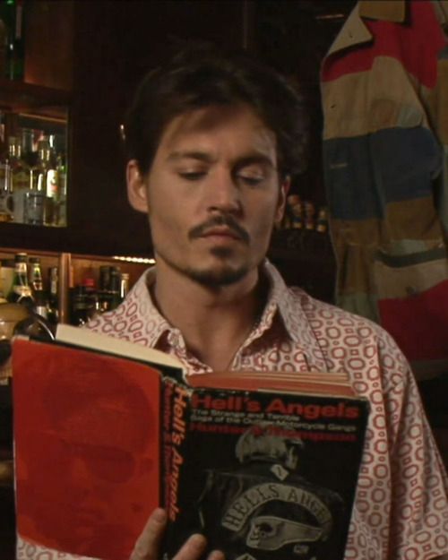 a man is holding a book in his hand and looking at it with an intense look on his face