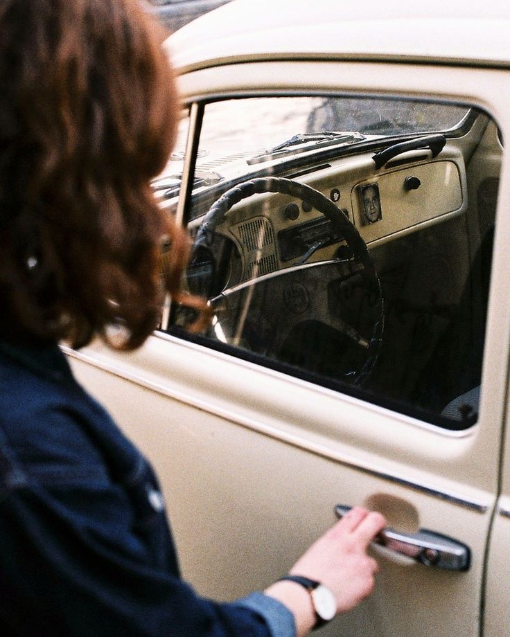 a woman is looking out the window of an old car