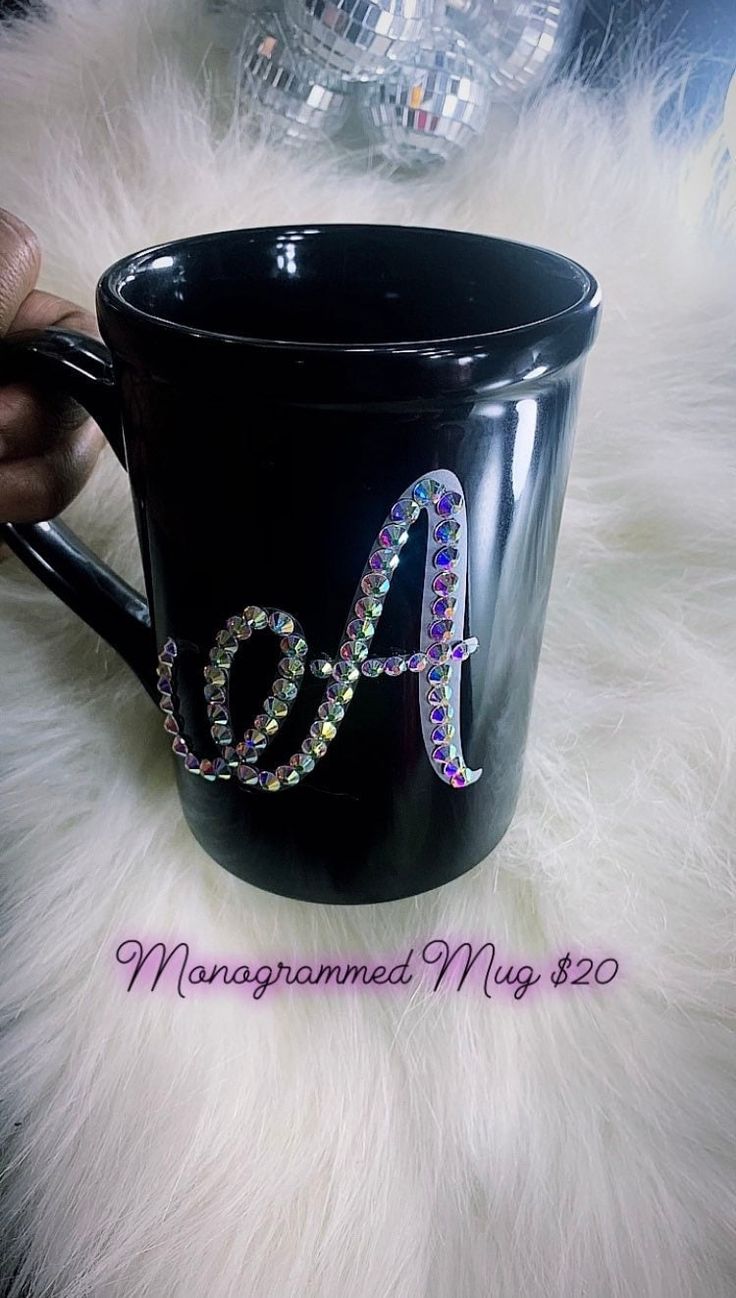 a black coffee mug with the letter a painted on it's side and beaded in