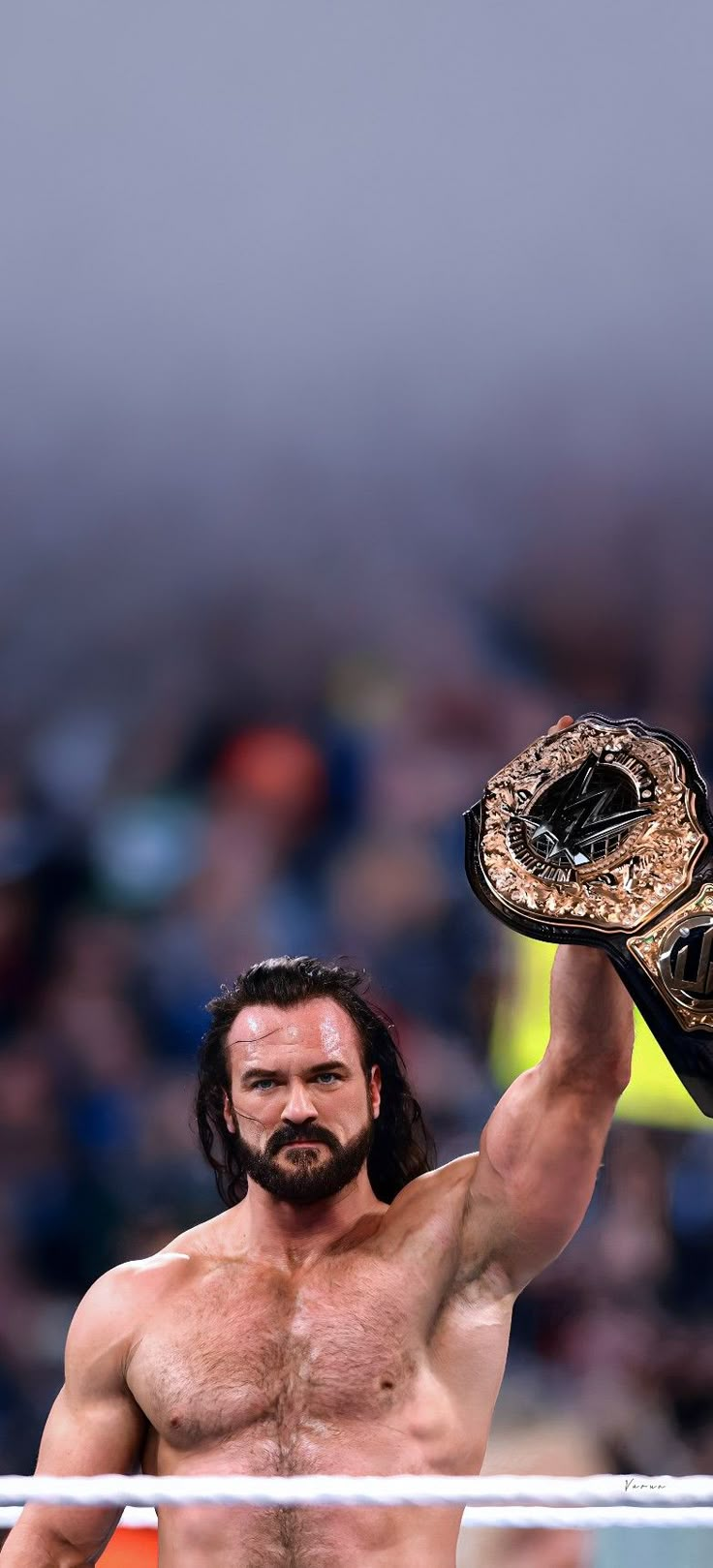 a shirtless man holding up a wrestling glove