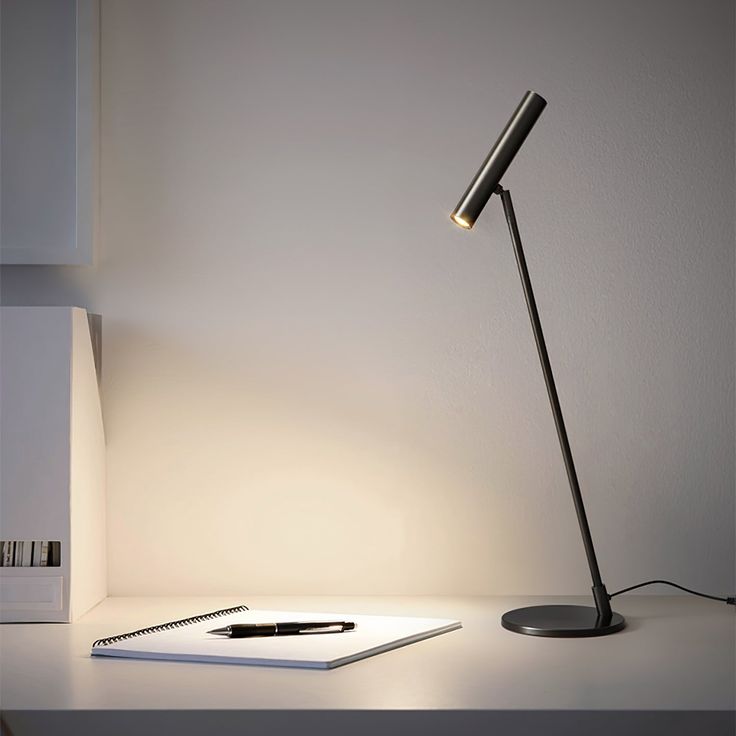 a desk lamp sitting on top of a table next to a laptop computer and pen