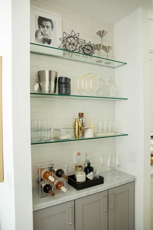 a kitchen with glass shelves filled with bottles and glasses on top of the countertop