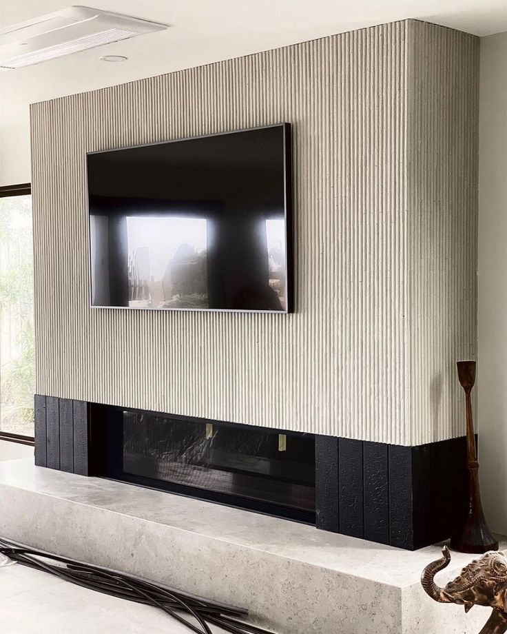 a flat screen tv mounted to the side of a wall next to a fire place