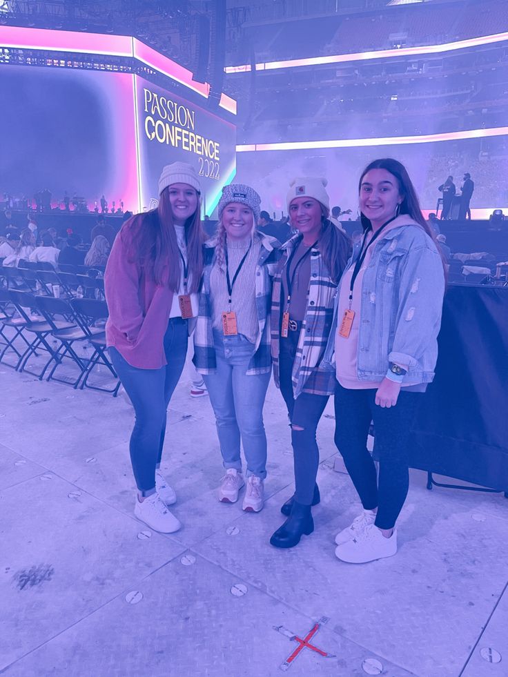 three girls are standing in front of a television screen at a convention or conference center