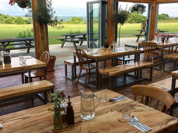 a restaurant with wooden tables and benches in front of large windows looking out onto the field