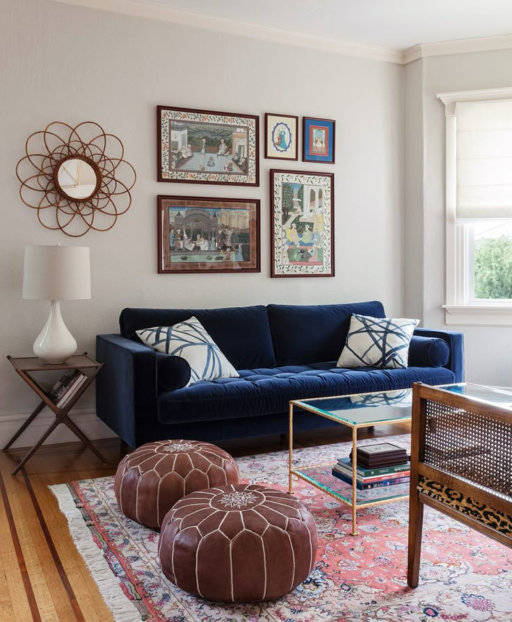 a living room with blue couches and pictures on the wall above them in various frames