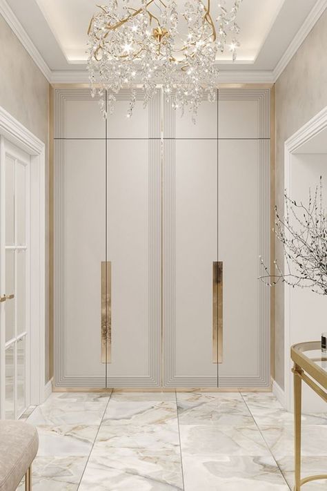 a white and gold hallway with chandelier, marble flooring and glass doors