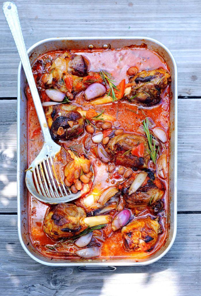 a large pan filled with food on top of a wooden table next to a fork