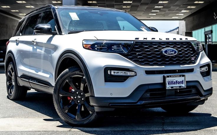 a white ford explorer is parked in front of a building with black tires and rims