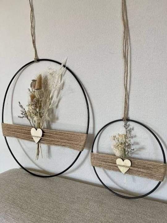 two circular wall hangings decorated with dried flowers and heart shaped wooden hearts are hung on the wall