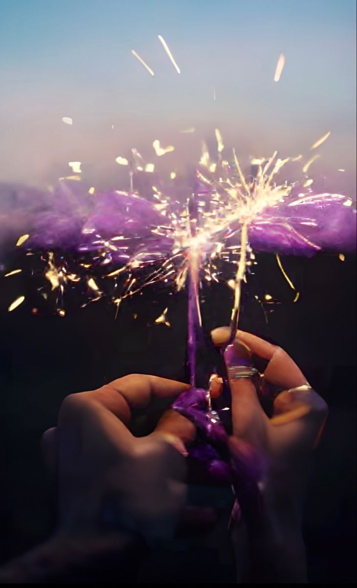 someone holding a purple sparkler in their hand