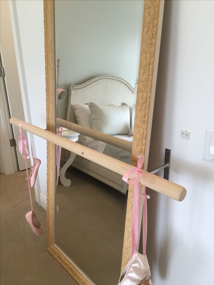 a mirror with pink ribbon hanging from it's side in front of a bed