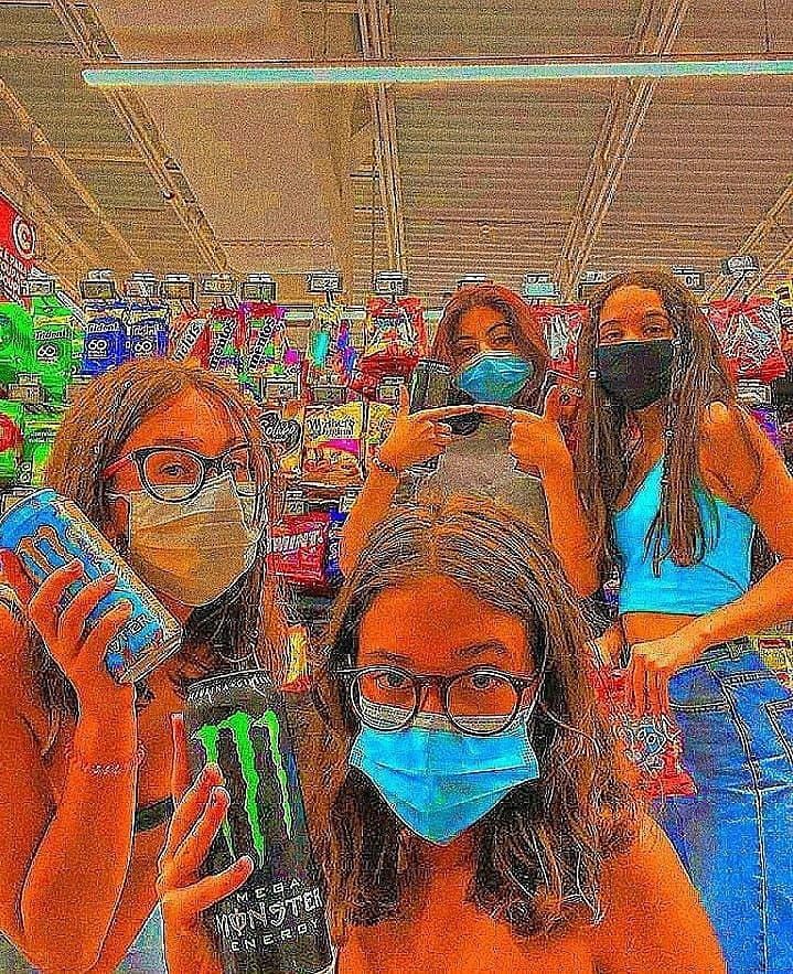 three girls wearing face masks while shopping in a grocery store with monster energy drinks on their faces