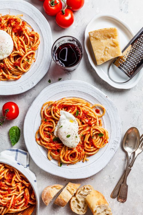 three plates of spaghetti with tomato sauce, bread and cheese on the side next to each other