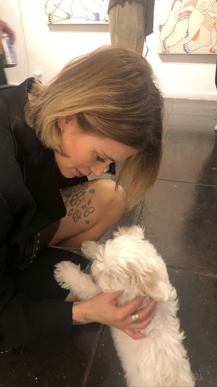 a woman petting a small white dog