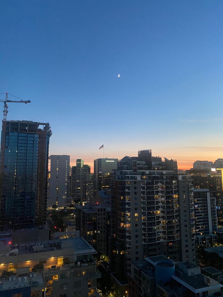 the city skyline is lit up at night, with skyscrapers in the foreground