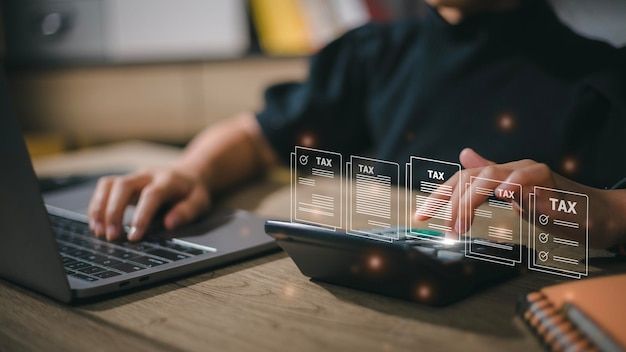 a person using a laptop on a table with an image of a tax form coming out of the screen