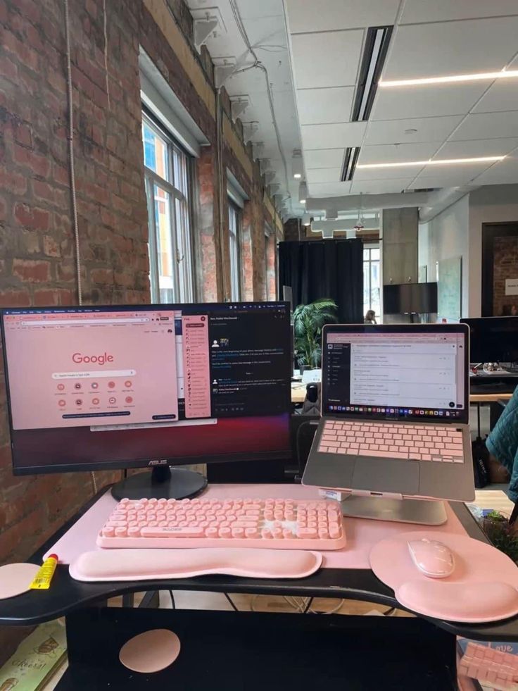 two laptops are sitting on a desk with pink keyboards and mouses in front of them