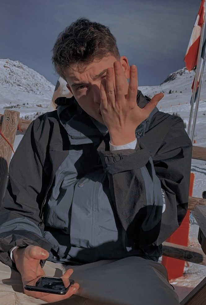 a man sitting in the snow holding his hand to his face