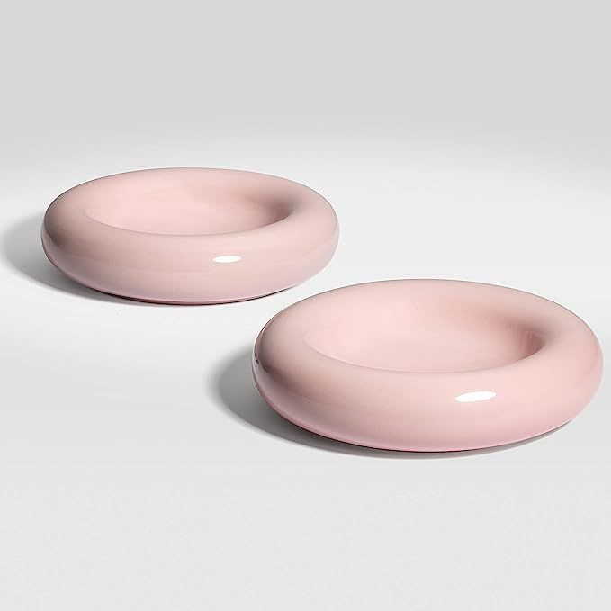 two pink plates sitting next to each other on a white surface with no one in it