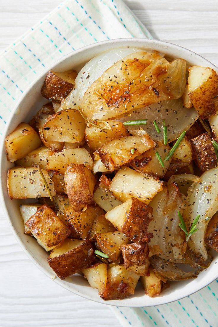 a white bowl filled with potatoes on top of a blue and white cloth next to a fork