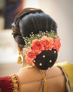 the back of a woman's head with flowers in her hair and beads on it