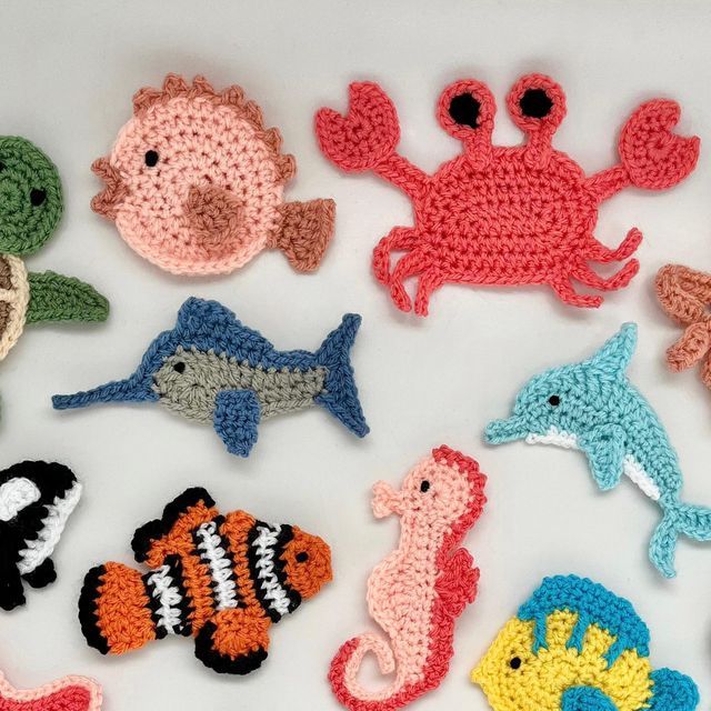 crocheted sea animals are arranged on a white surface, including an octopus, fish, and crab