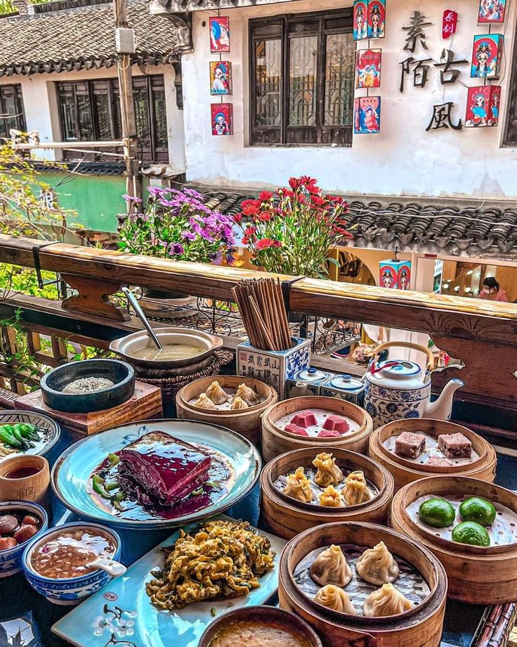 a table filled with lots of food on top of a wooden table next to a building