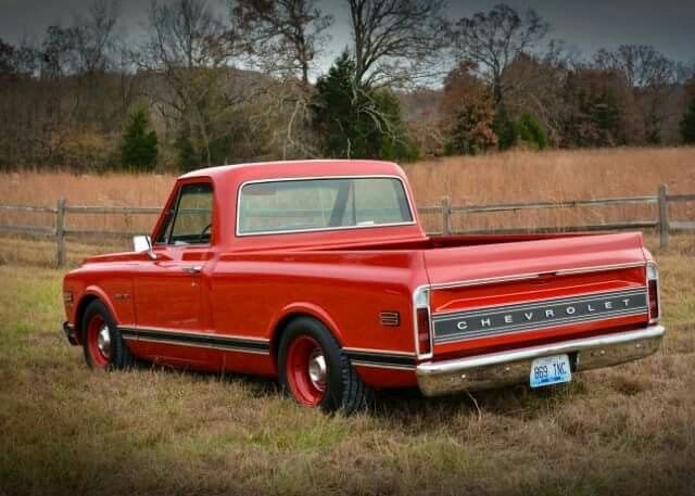 an old red pickup truck parked in a field