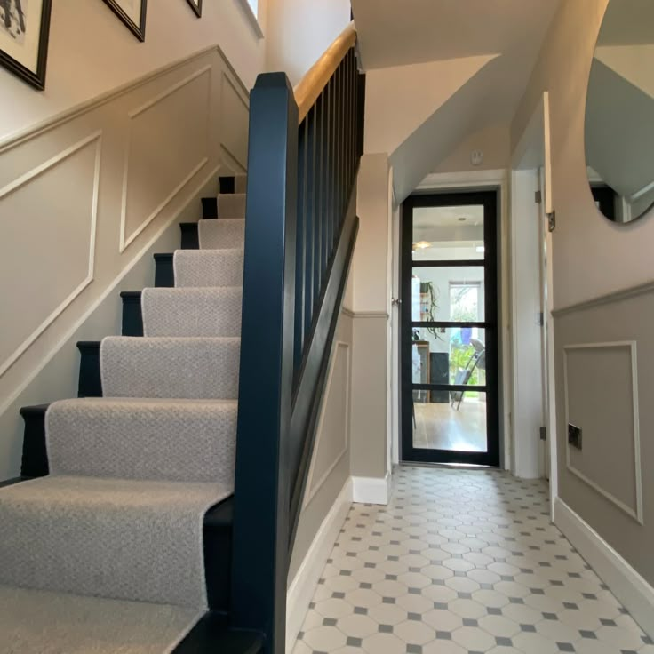 a hallway with stairs and framed pictures on the wall above it, along with a door leading to another room