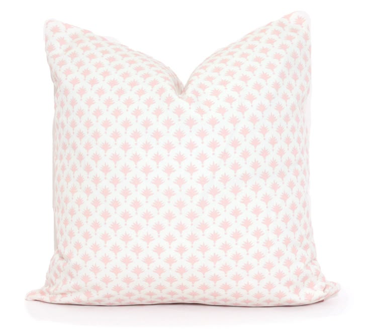 a pink and white pillow with small flowers on the front, against a white background