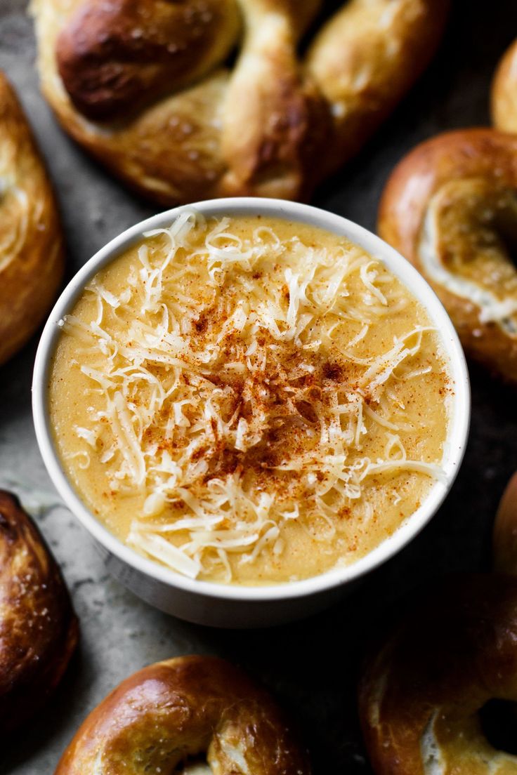 a bowl of soup with cheese on top surrounded by bagels