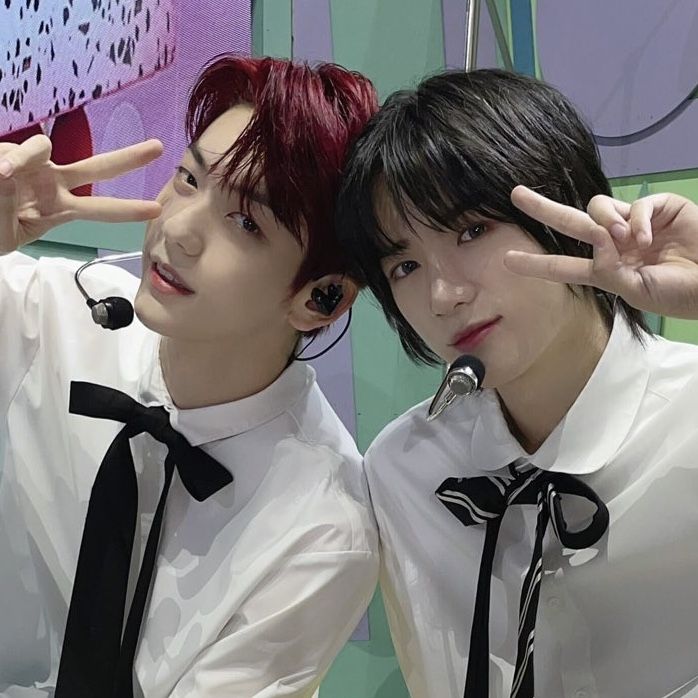 two young men wearing white shirts and black ties posing for the camera with their fingers in the air