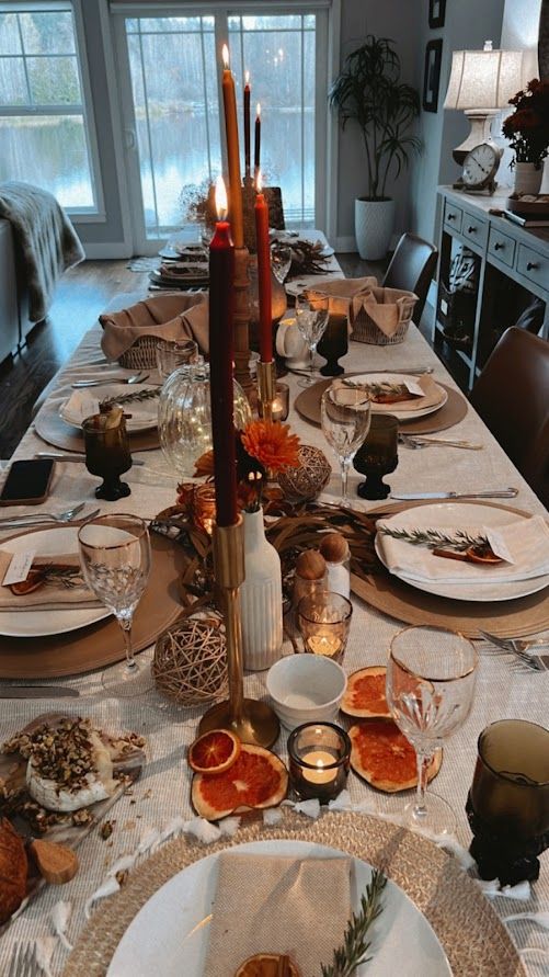 a dining room table is set with plates and candles