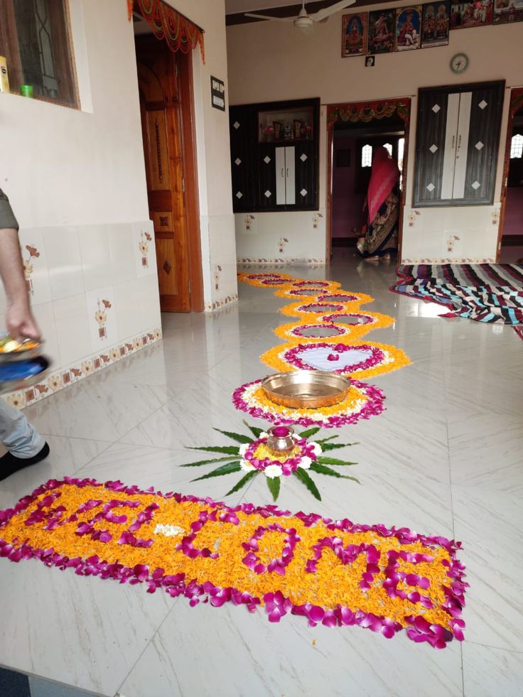 a man walking down a hall with flowers on the floor