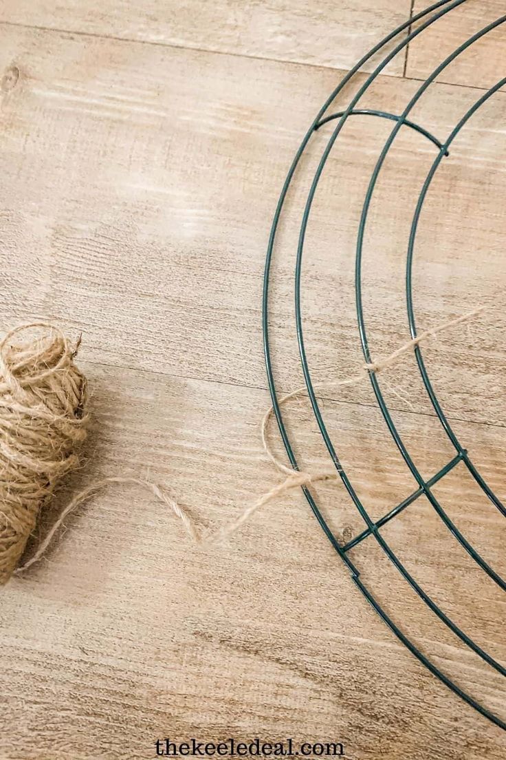 a piece of twine is sitting on the floor next to a wire rack and ball of yarn