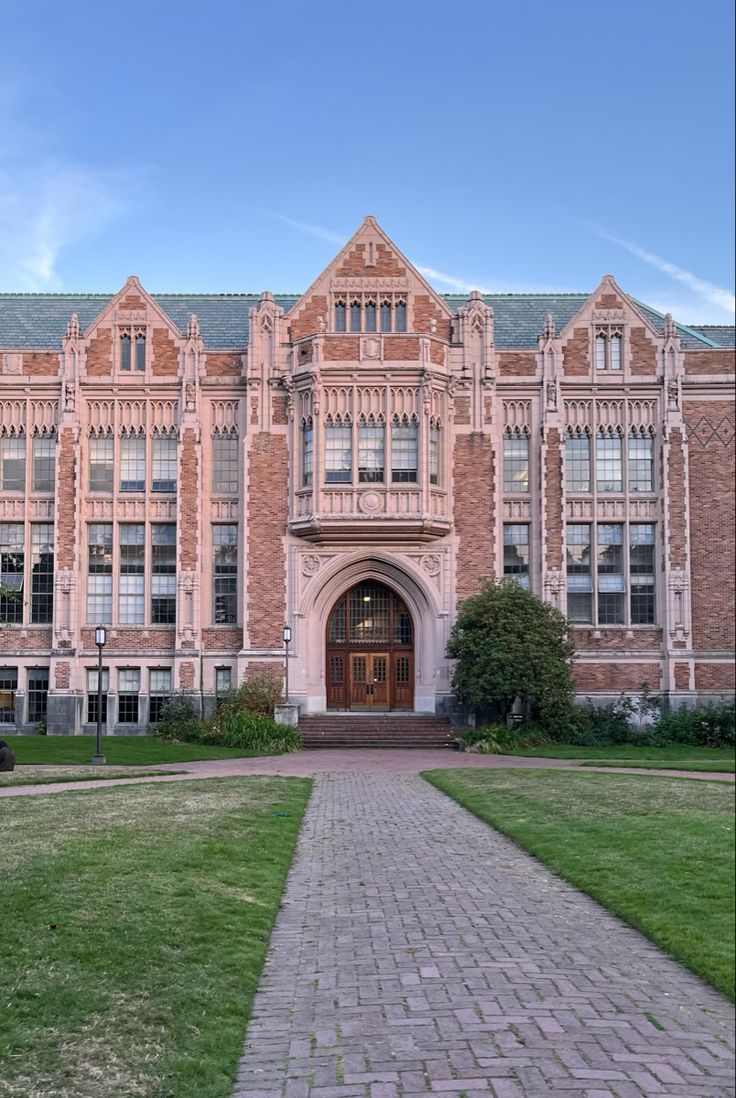 an old brick building with a walkway leading to the front door and grass in front