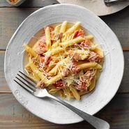 a white plate topped with pasta covered in sauce and cheese next to two silver spoons