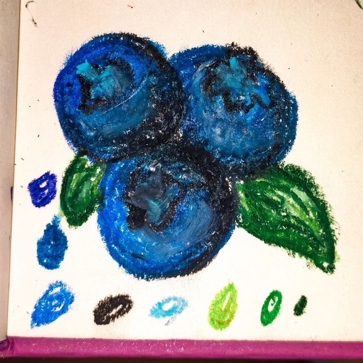 some blueberries are sitting on top of a piece of paper with colored crayons