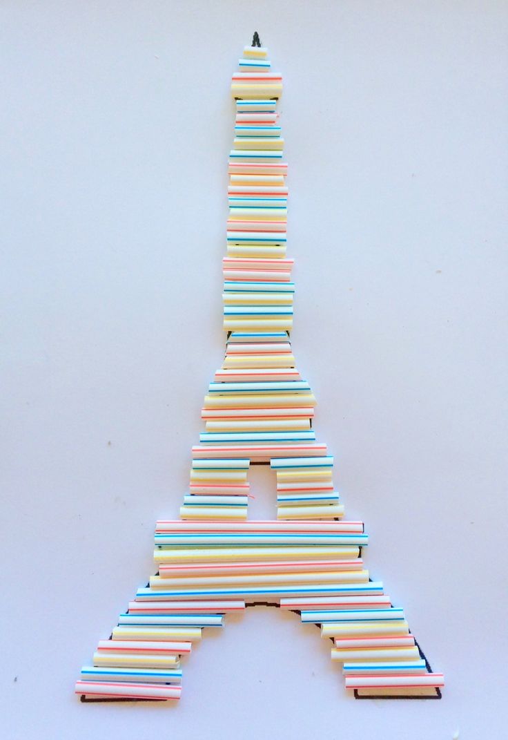 the eiffel tower is made out of strips of colored paper and sits on a white surface