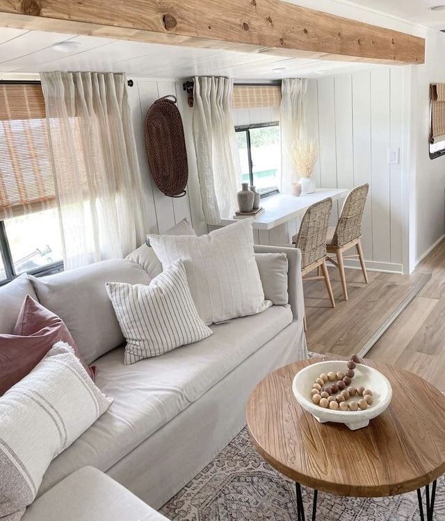 a living room filled with furniture and a wooden table in front of a kitchen area