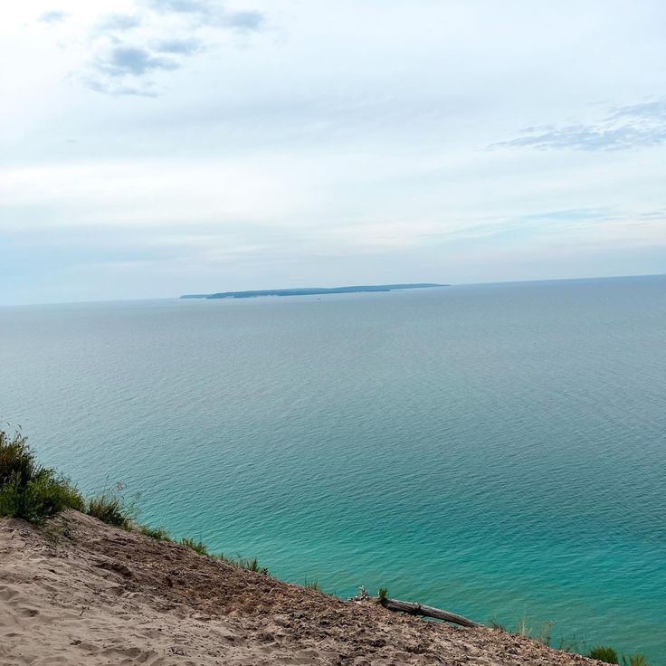 a bench sitting on top of a sandy hill near the ocean