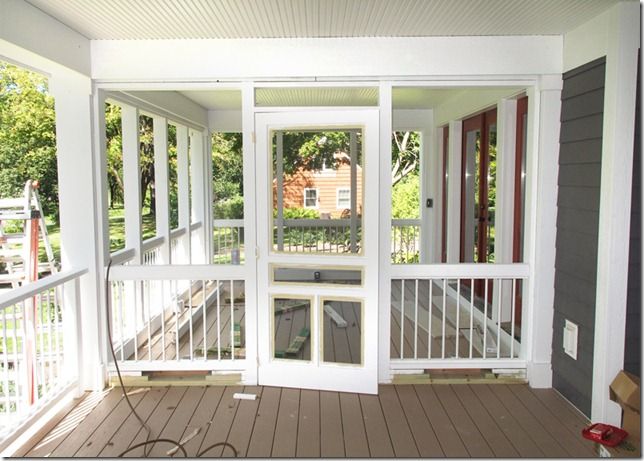 an empty porch with white railings and doors